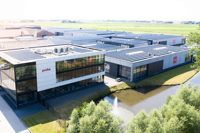 Luchtfoto van het pand van Probo met zonnepanelen op het dak, omringd door groen en water.