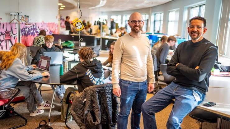 Studenten werken aan laptops in de open werkruimte van MICA, met twee begeleiders op de voorgrond.